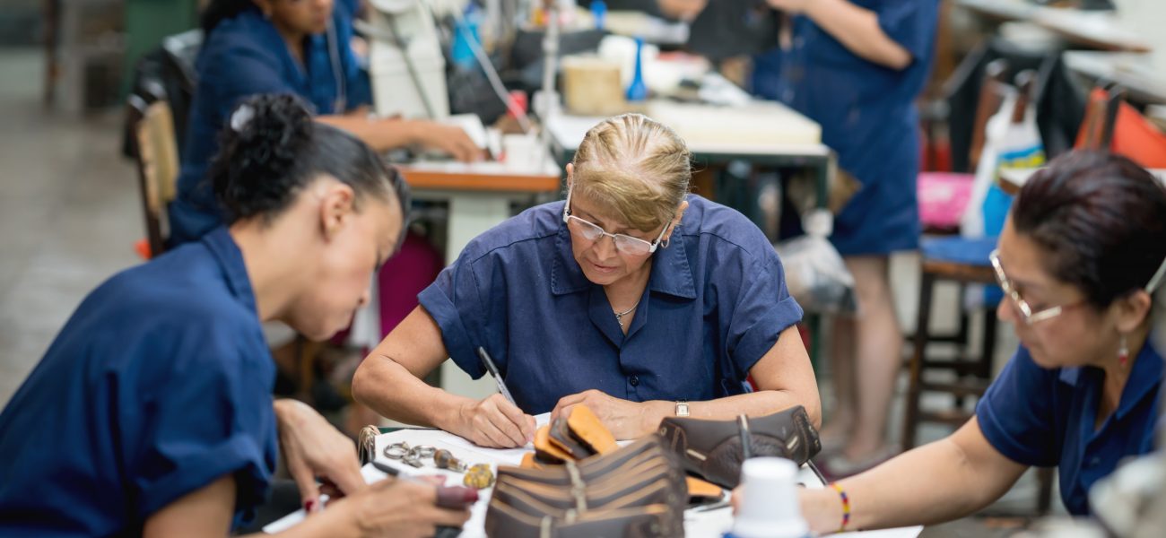 Group of Latin American women working at a shoe making factory - manufacturing concepts