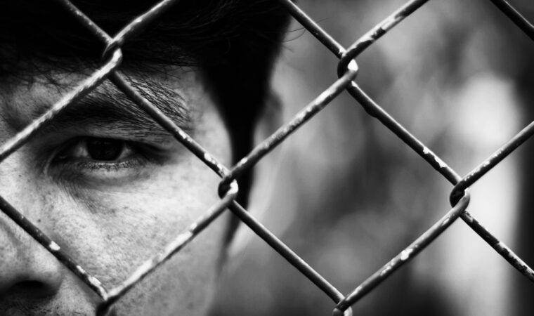 Depressed man standing behind a fence ,close up on face
