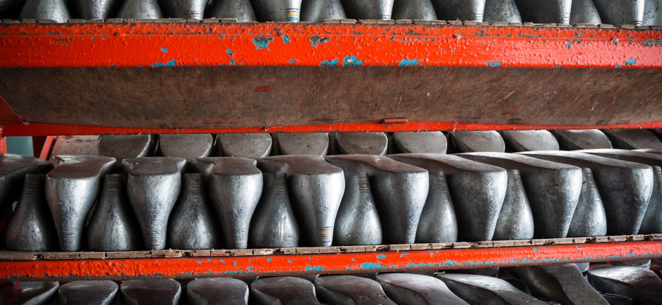 Lines of aluminum shoes last with a rough surface prepare on shelf in a shoe factory.