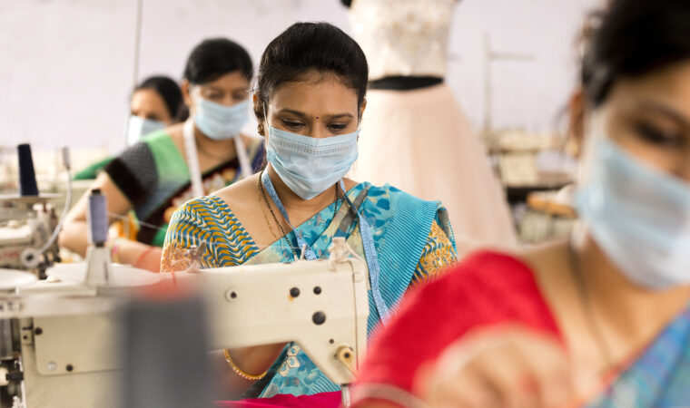 Indian woman textile workers with protective face mask on production line