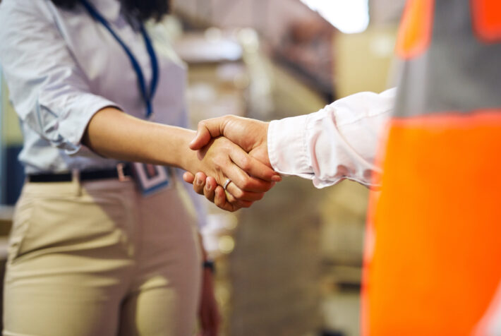 Logistics, deal and handshake with business people in warehouse for shipping, cargo and supply chain contract. Thank you, partnership and support with worker in factory plant for b2b distribution