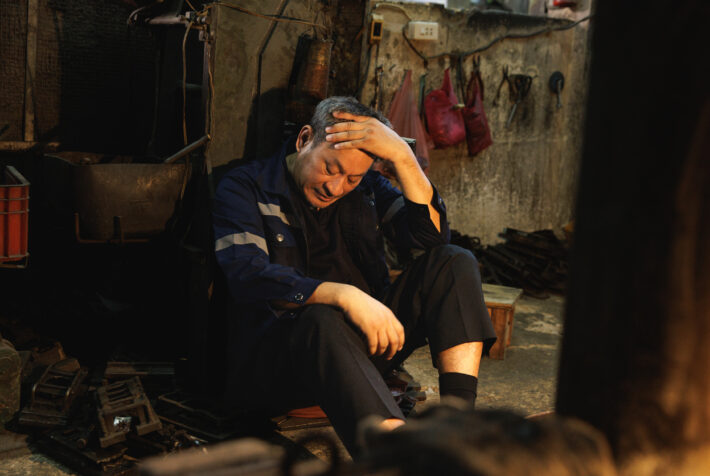 Stressed senior factory worker suffering from headache or fatigue.